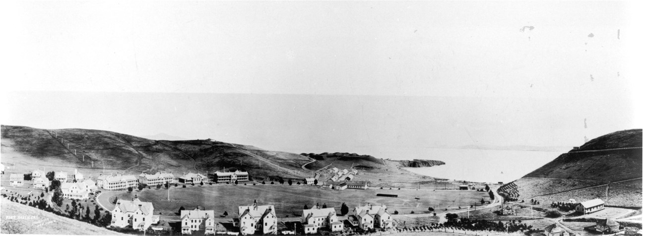 small historic buildings clustered around open landscape with ocean in the background