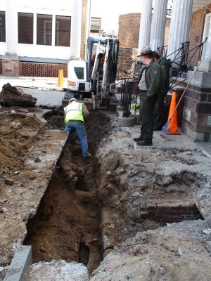 Park rangers supervise resource-sensitive construction work at Fort Jay.  Revealed within the trench are an old ceramic pipe and a circular brick air shaft into one of the subterranean chambers.
