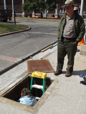 Park personnel explore the entrance to a similar vault on the opposite side of the Fort Jay quadrangle.