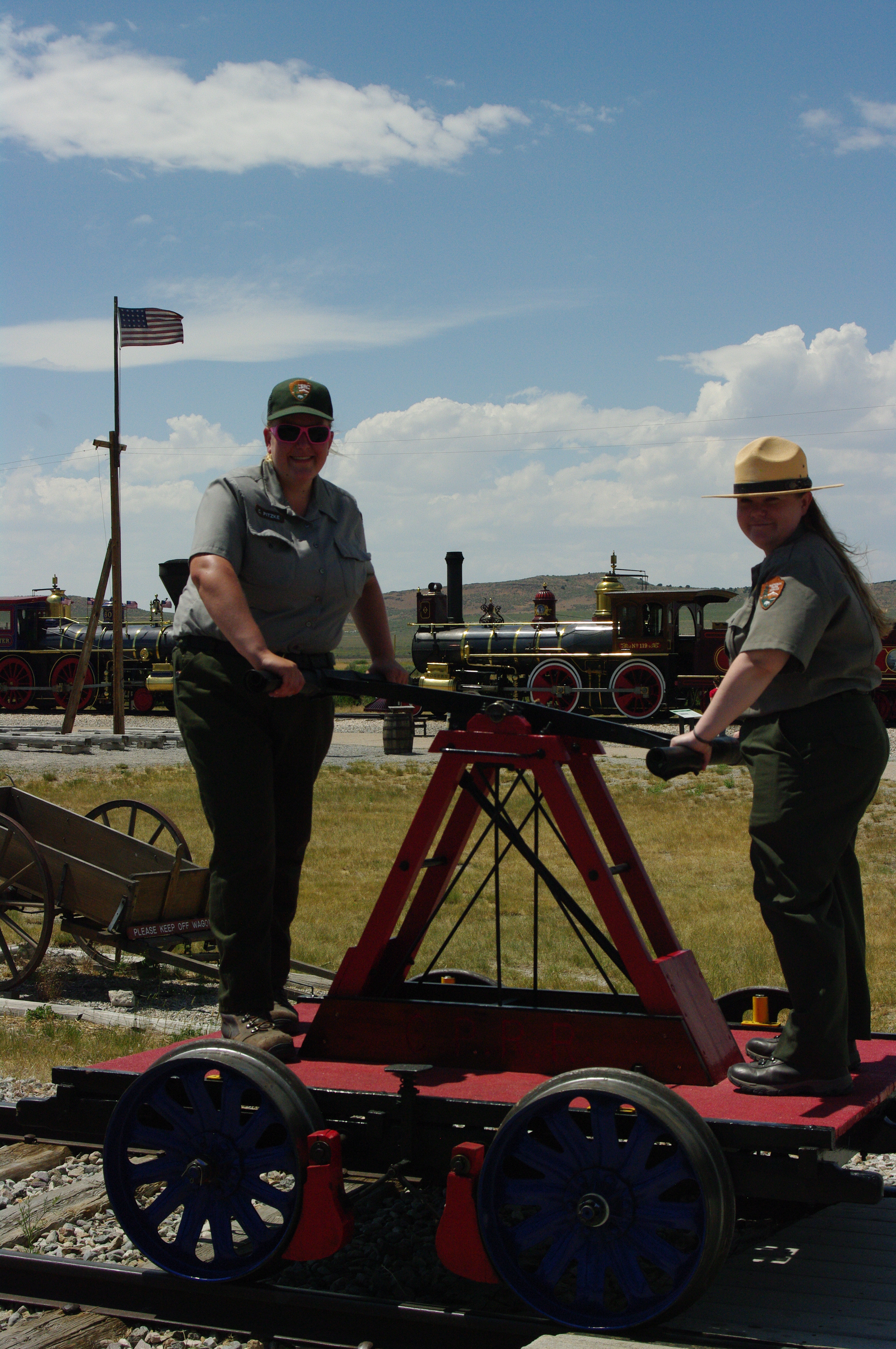 Two rangers operating hand car on railroad siding.