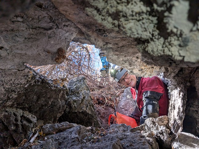 smiling person crawling in cave entrance
