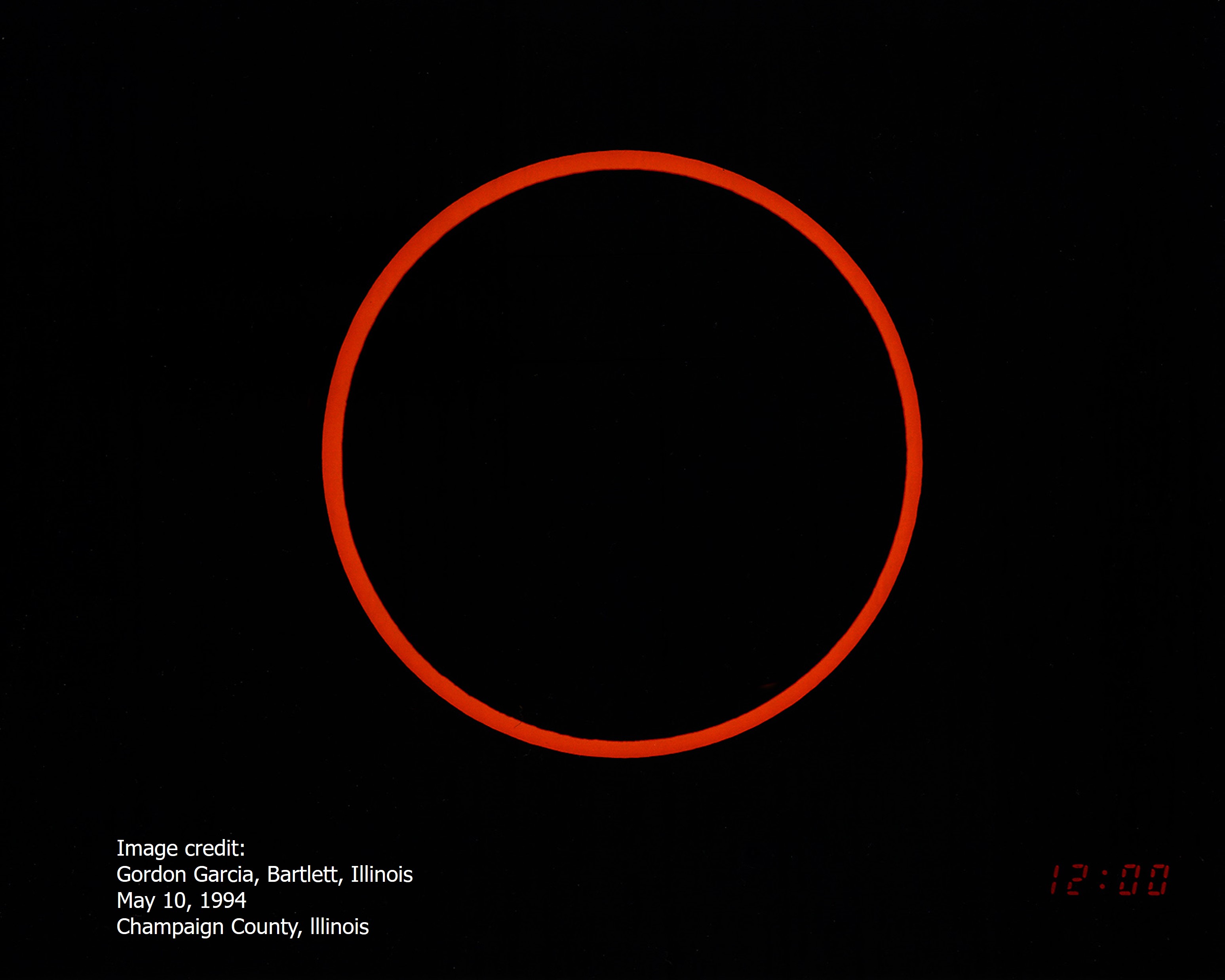 A field of black is broken by a singular, thin orange ring around a black center