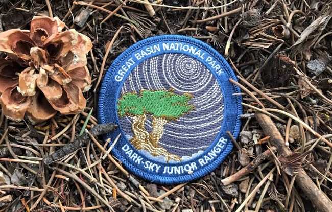 Junior ranger Dark-Sky patch with star trails and a bristlecone