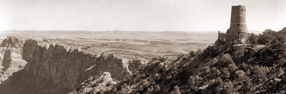 Sepia toned image of Desert View Watchtower on the far right, looking out over Grand Canyon cliffs beyond.