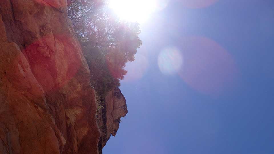 view seen by heat exhausted hiker looking up at canyon cliffs with sun glaring down at midday. 
