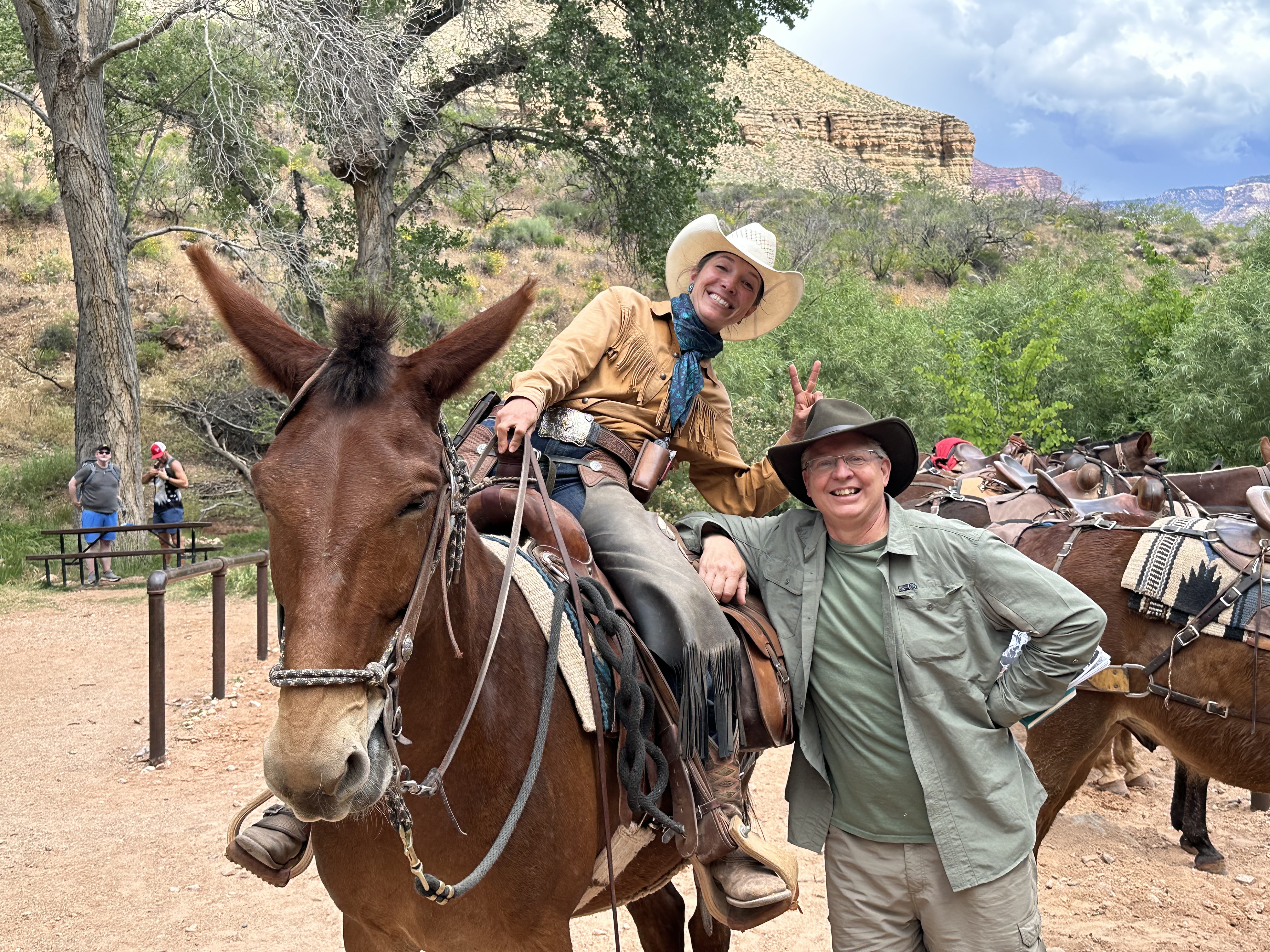 A man stands next to a woman on a mule.