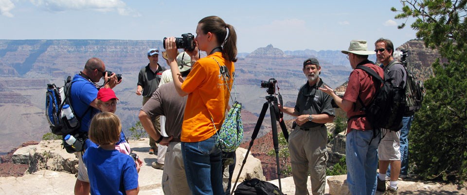 A group of photographers with tripods mingle on a scenic overlook.