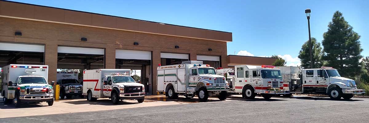 A row of five Grand Canyon National Park Emergency Vehicles parked in front of their garages.