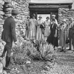 Park ranger with group of people in front of stone building