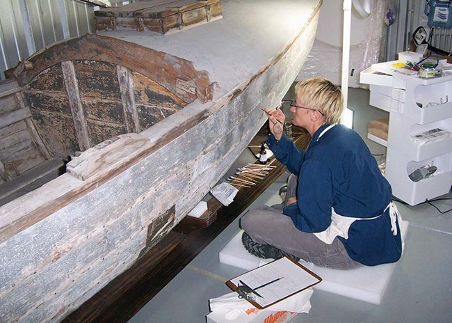 Touching up the white paint-job on a wooden boat