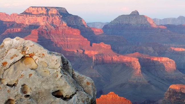 Grand Canyon rock formations turned pink and blue by the sunset.