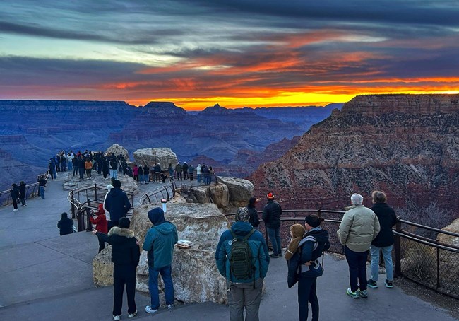 A group of visitors stand at Mather Point to watch the canyon sunrise