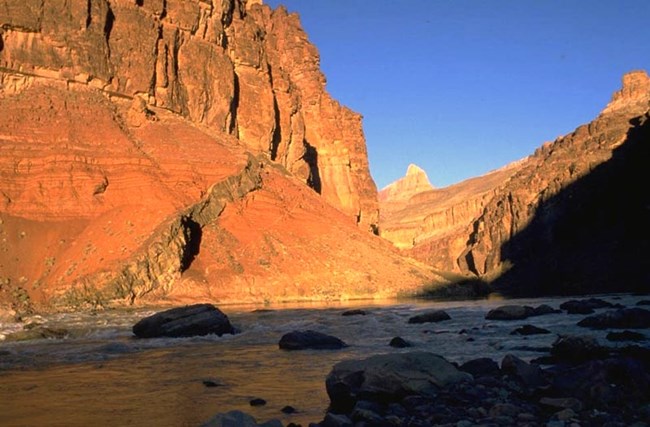 Colorado river water in the shade below orange cliffs.