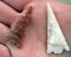 A red and a white projectile point in hand.