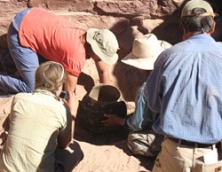 Four archeologists examine a prehistoric pot.
