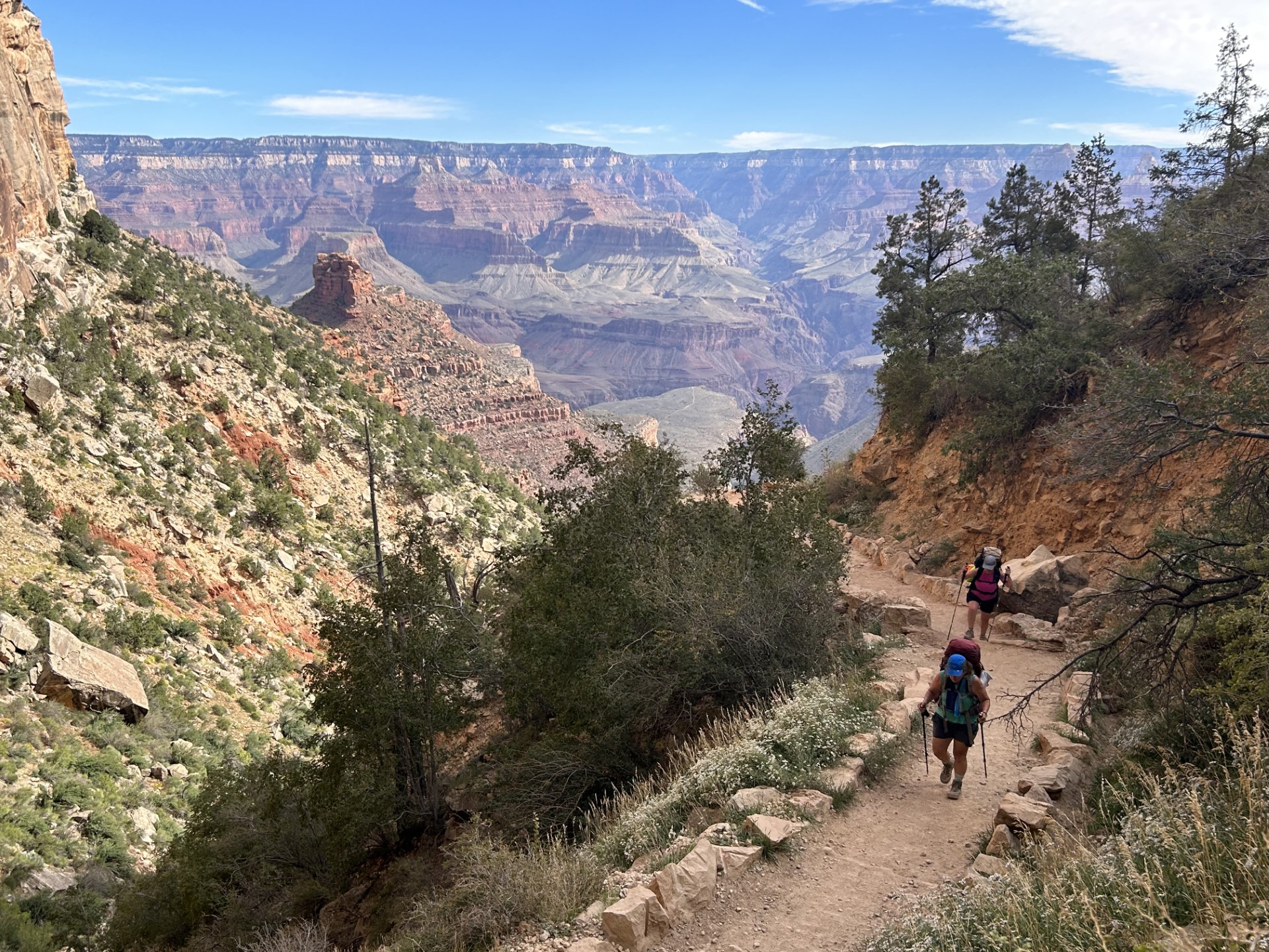 Two hikers ascend the Bright Angel Trail carrying heavy backpacks