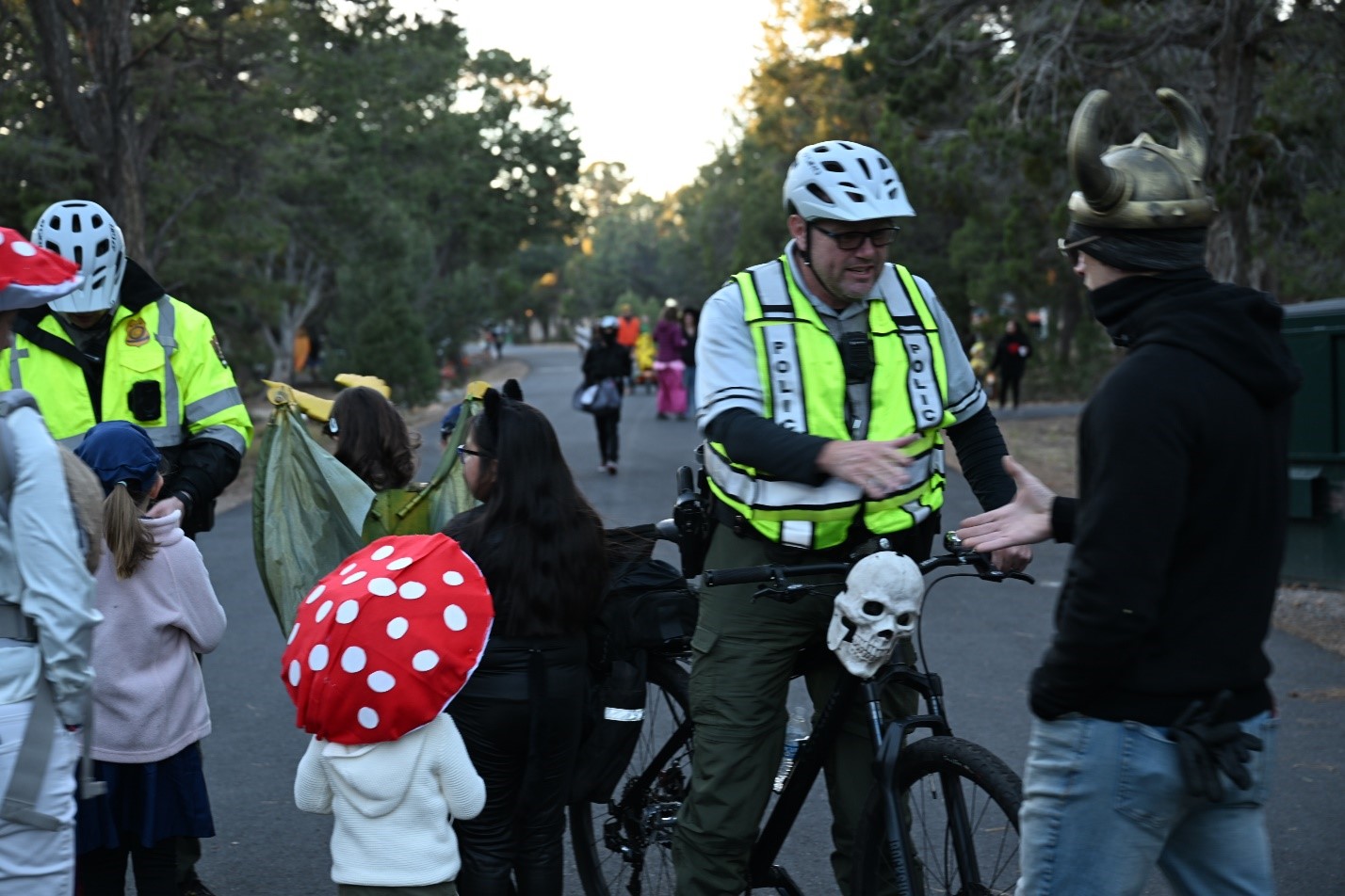 Two rangers in reflective vests interacts with trick-or-treaters on a city street during Halloween
