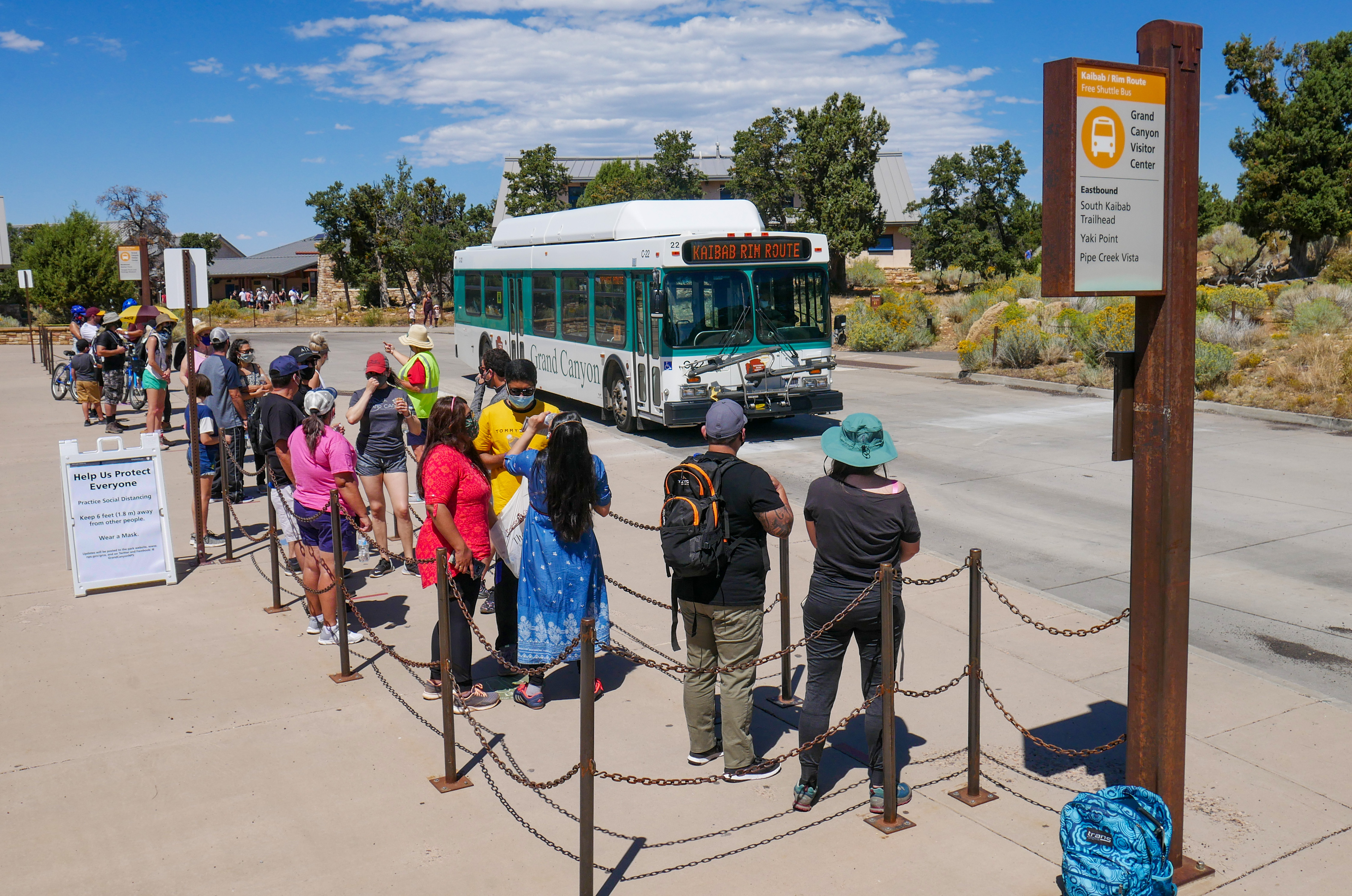 Visitors stand in line waiting for a shuttle bus at the Grand Canyon Visitor Center