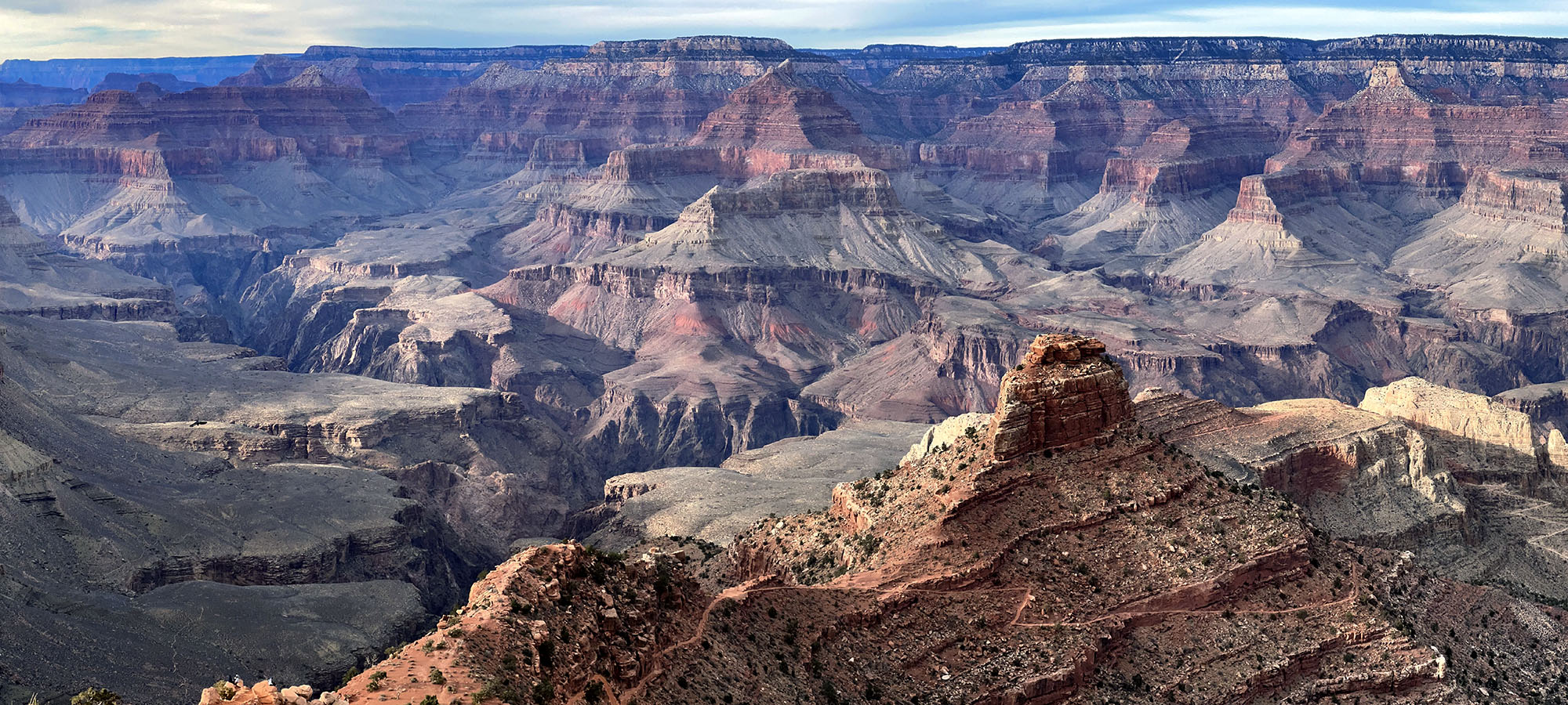 A canyon landscape with a trail winding down a ridgeline.