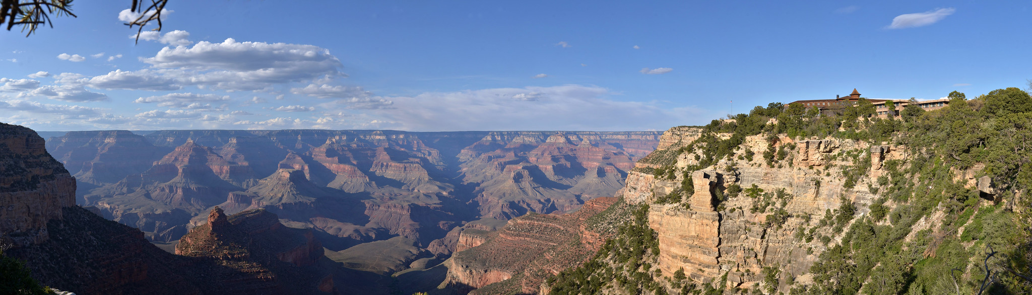 A brown hotel sits on the edge of the canyon in a panoramic landscape view