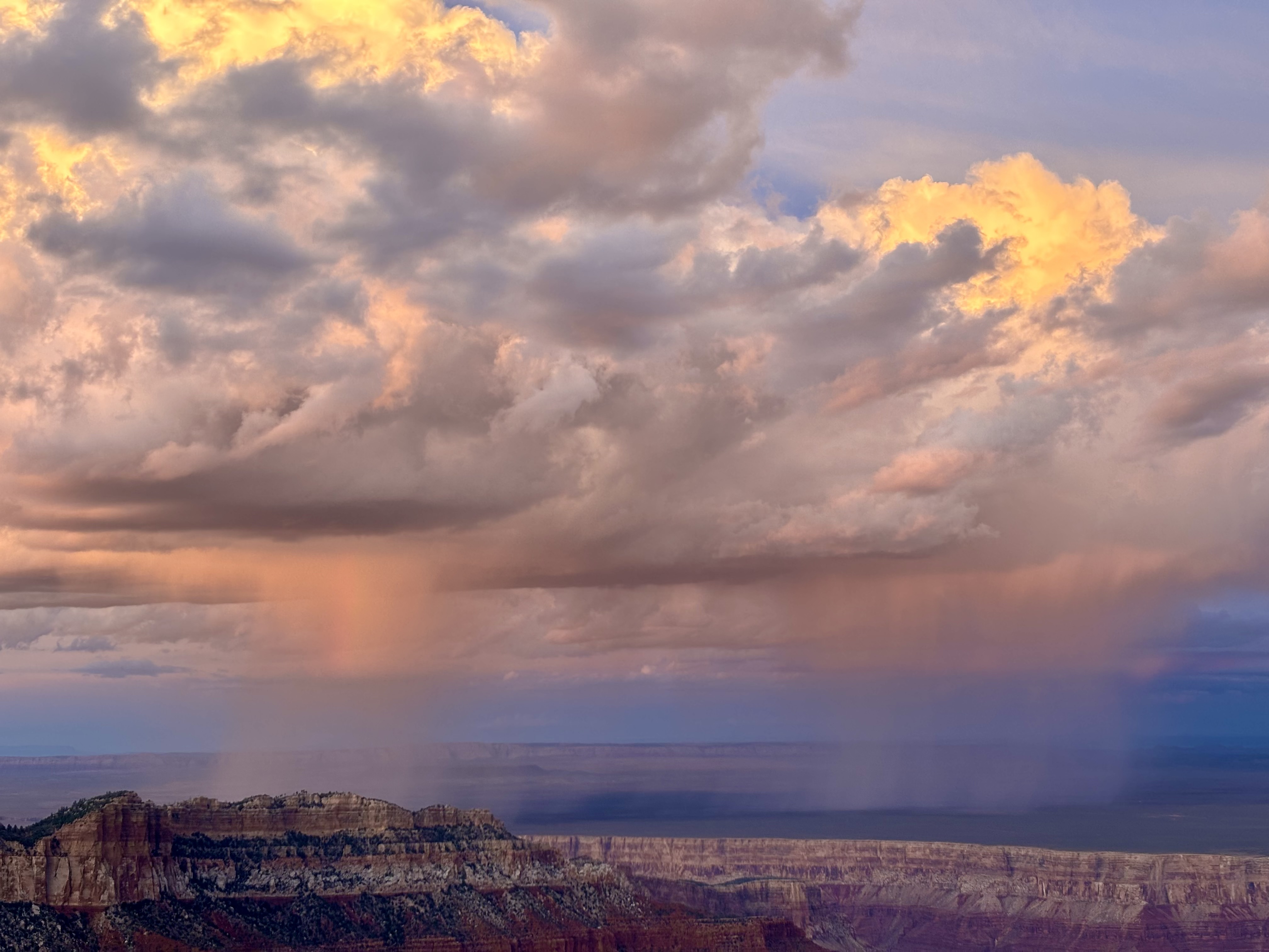 A peak in the inner canyon stands out among pink and blue rainclouds