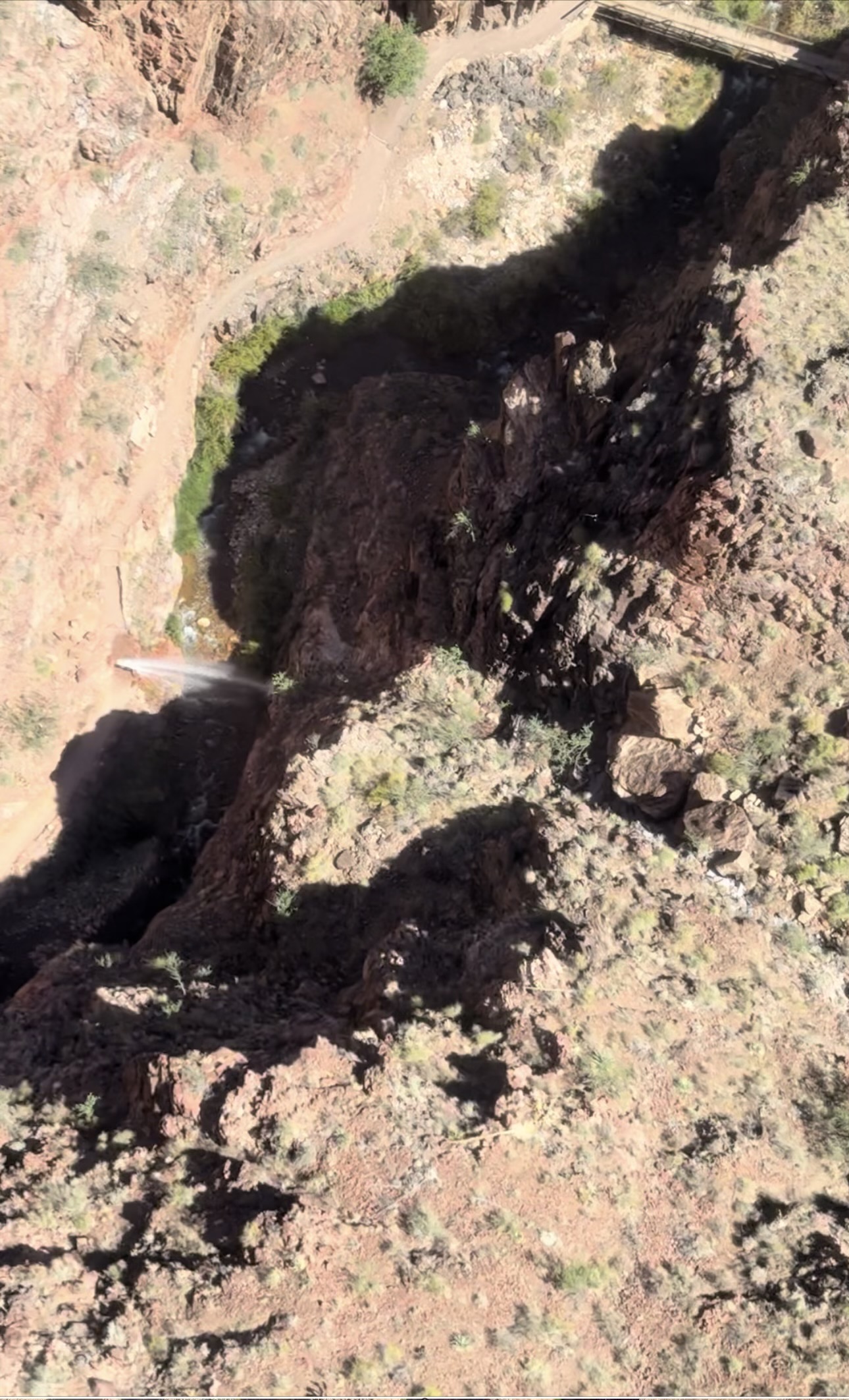 A massive geyser of water is seen shooting out of a canyon trail