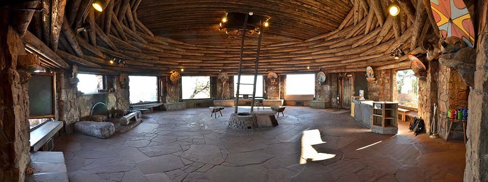 A wide open circular room with a flagstone floor. Large picture windows take up about 2/3 of the circumference of the circle. Windows are separated by stone pillars. The ceiling is made up of inter-woven logs that surround, then arch over the round room.