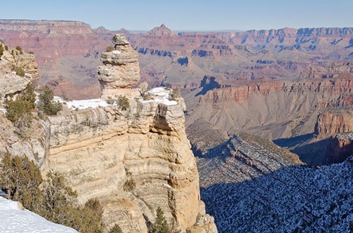 Rounded pale rock formation against Grand Canyon in the background.