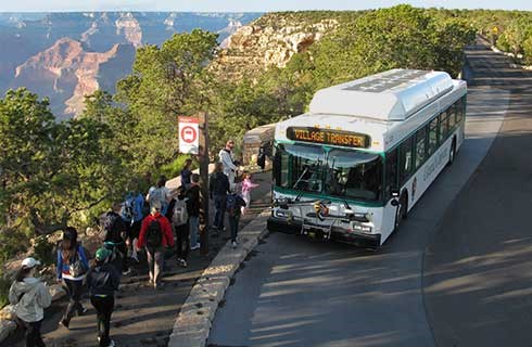 Shuttle bus passengers boarding at Hermits Rest. Grand Canyon beyond.