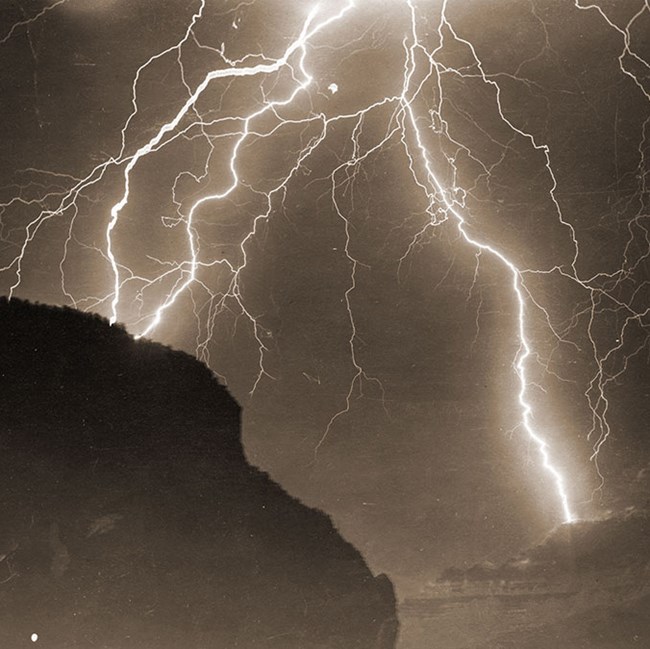 Sepia toned historic photo of multiple lightning strikes. Rim is in silhouette