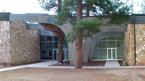 Large two-story building with stone walls and two, large arches that frame entryway walls with glass doors and floor to ceiling windows.