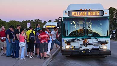 visitors boarding the Village Loop Shuttle Bus at dusk.