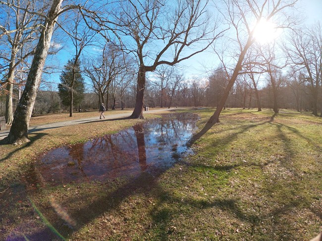 A man walks along the trail next to the shallow Patowmack Canal in Great Falls Park picnic area