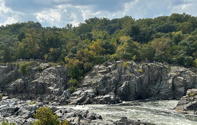 Rocky outcrops of gray rocks above blue river with white-capped waves