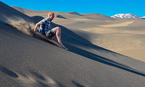 Man Sand Sledding on a Dune