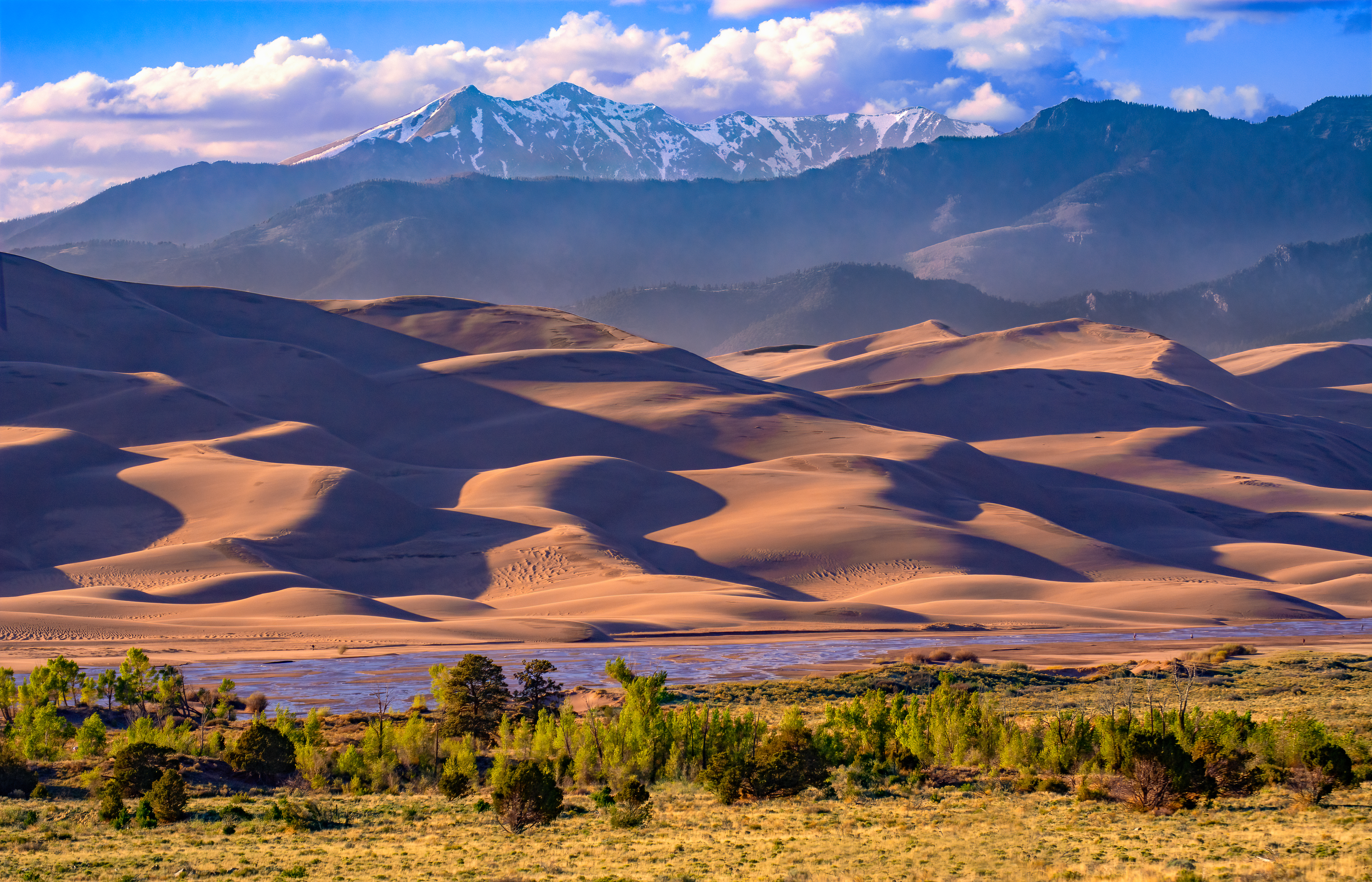 View from the Visitor Center of Grasslands, Trees, Medano Creek, Dunes, and Snow-Capped Cleveland Peak