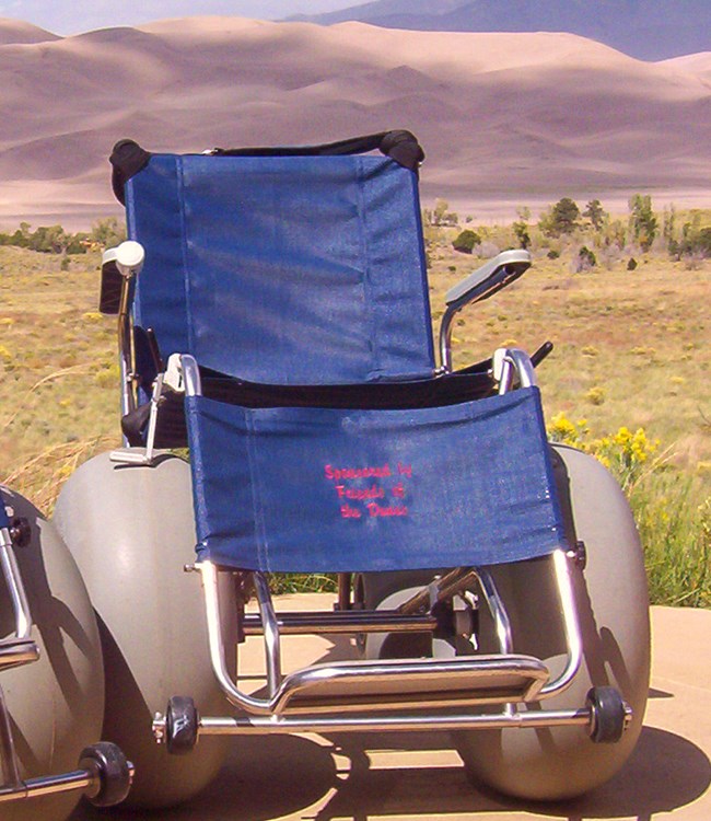 A specially designed wheelchair with balloon tires, dunes in background