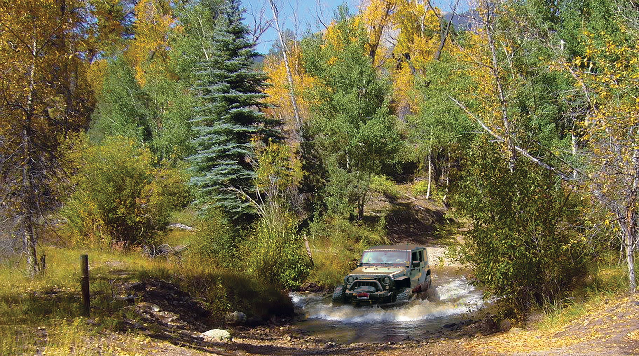 A Jeep crossing a mountain stream in a forest