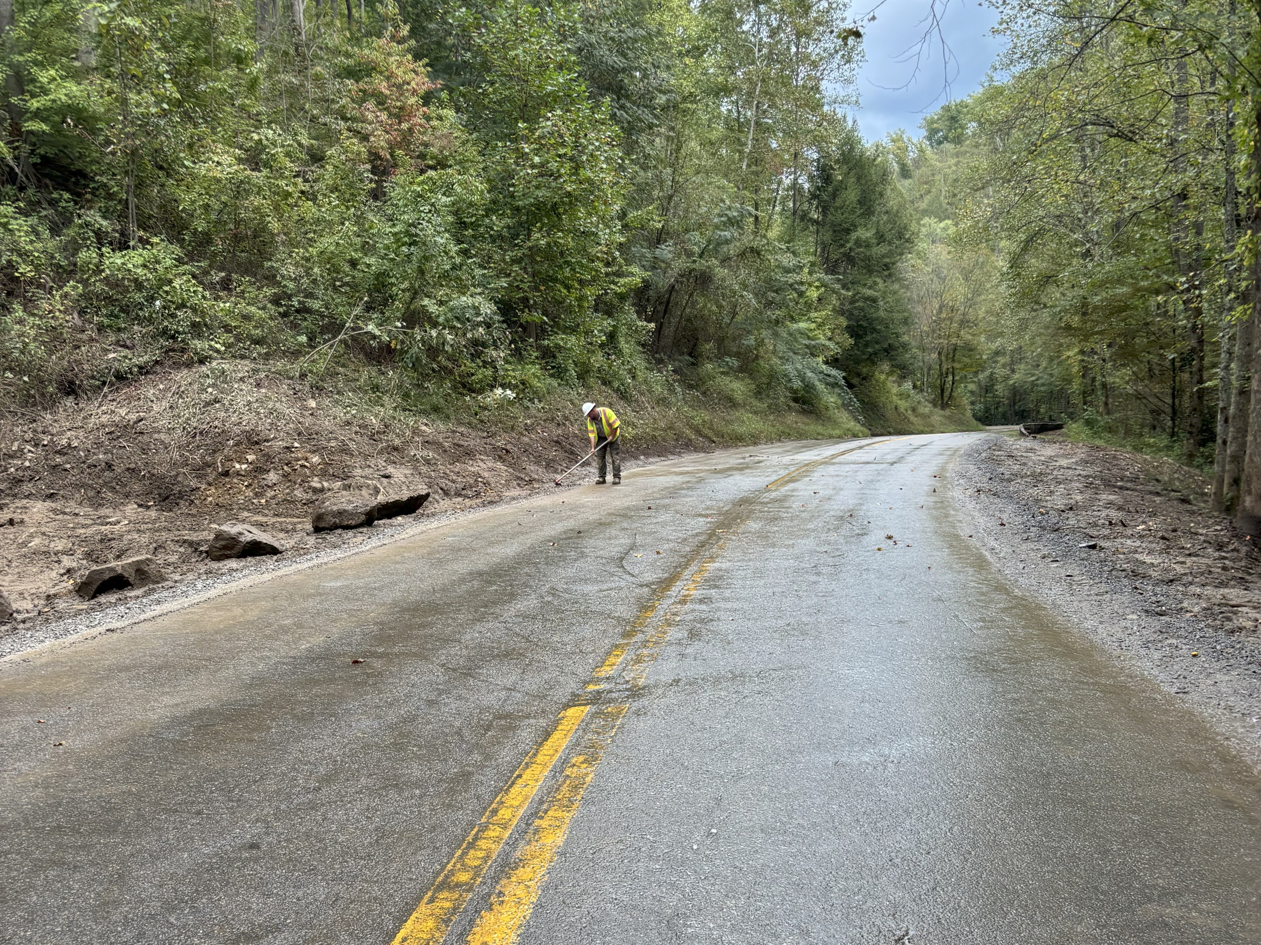 A man clears last debris off the side of a roadway.