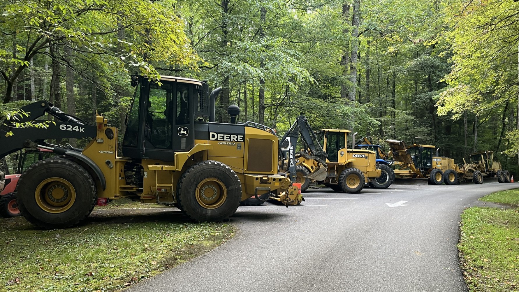 A few yellow park tractors and road equipment parking in parking area.
