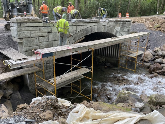 A crew working on replacing aculvert along a roadway.
