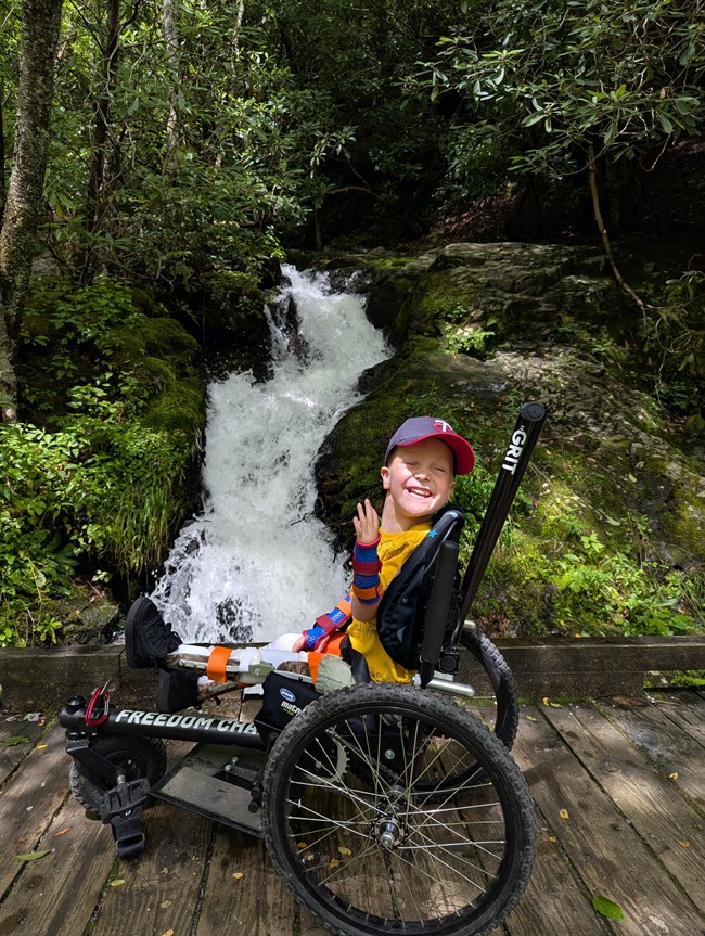 A child in a wheelchair at a waterfall.
