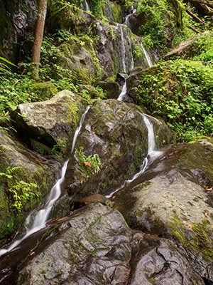Water trickles around boulders on a rock face.