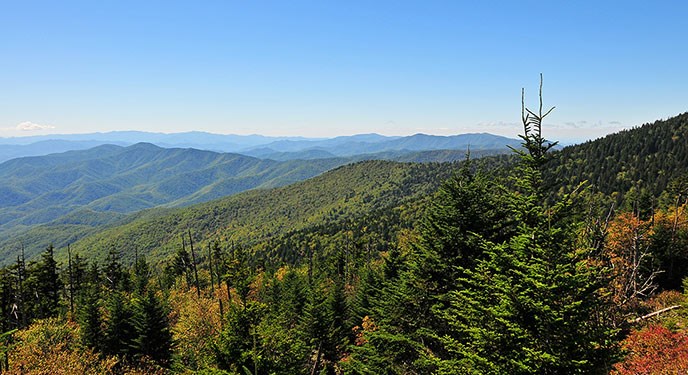 Forested mountains stretch to the horizon under a clear blue sky.