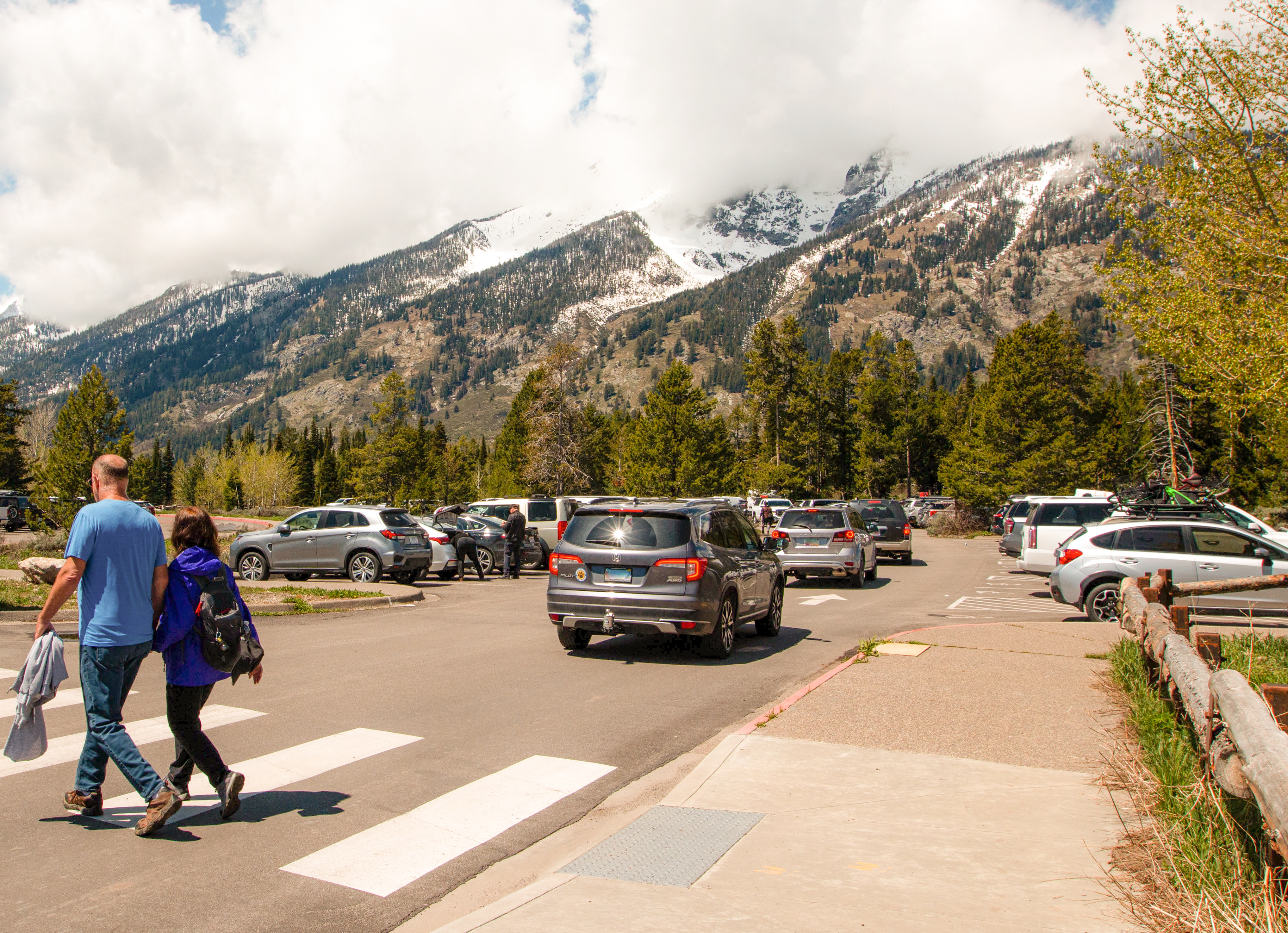 Parking at Jenny Lake, cars in parking lot with cloud covered mountains in the distance