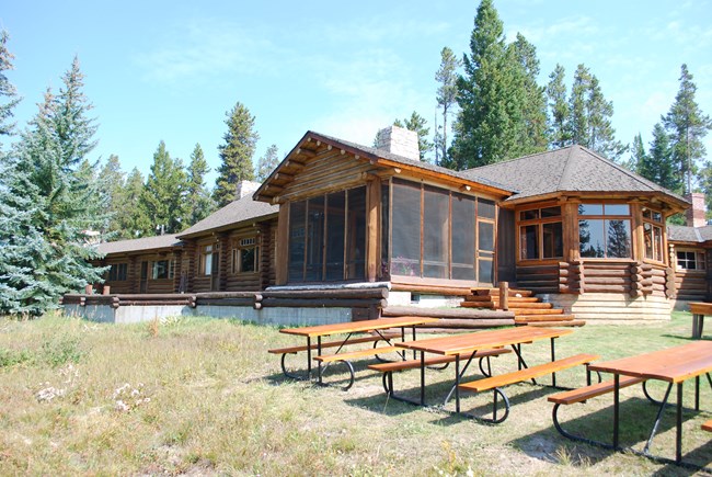 A log building with picnic tables out front.