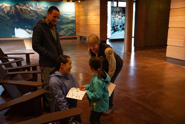 A ranger talks to a family in a building.