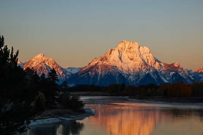 Sunrise on a river with mountains behind.