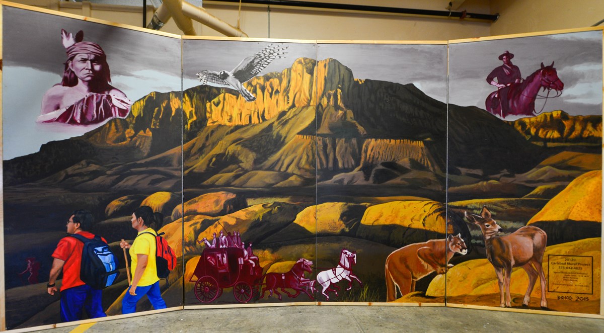 Mural with purple and brown colors depicting a mountain range, animals, and people.