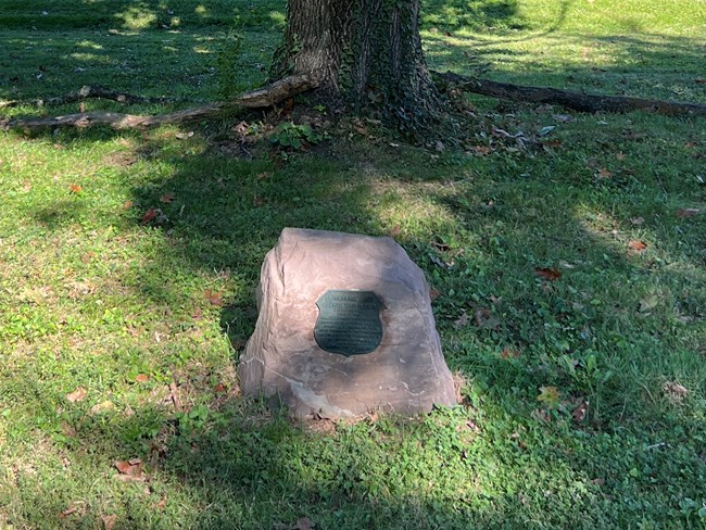 A plaque attached to a stone.